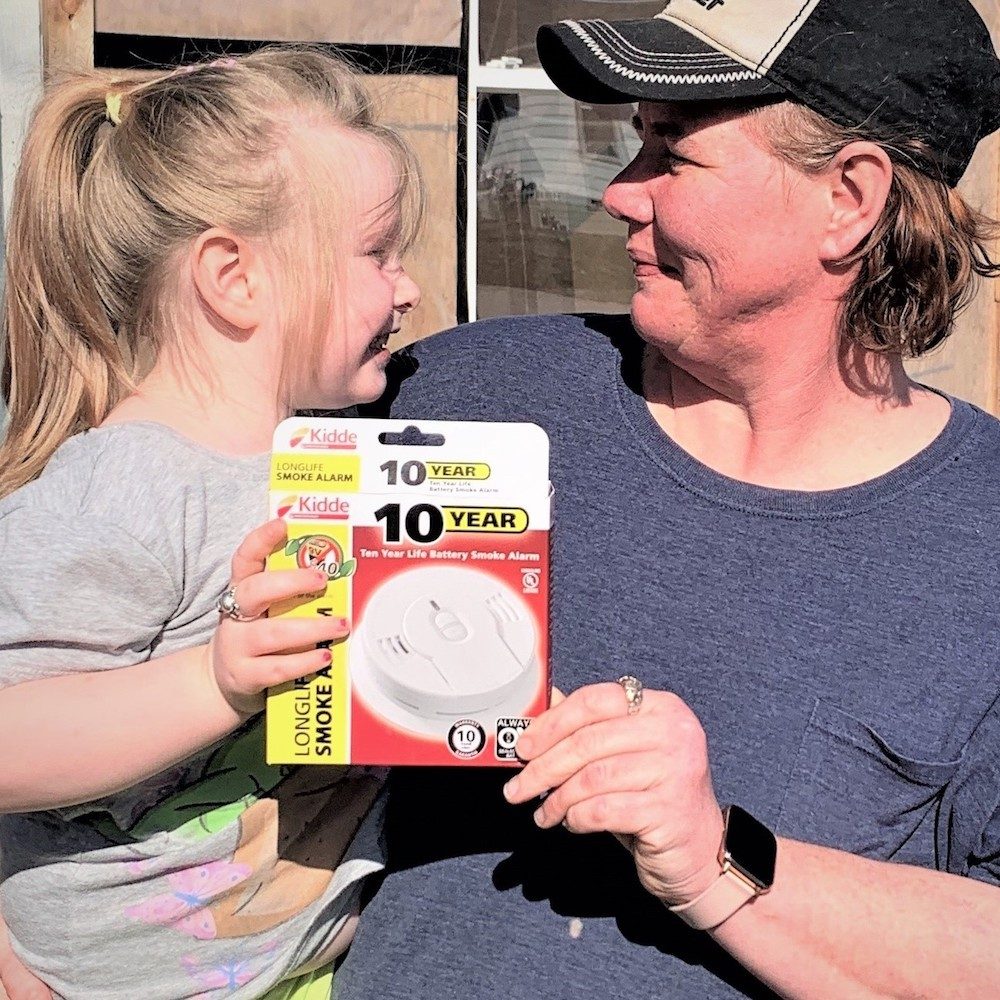 Mother holding a child and also a smoke alarm