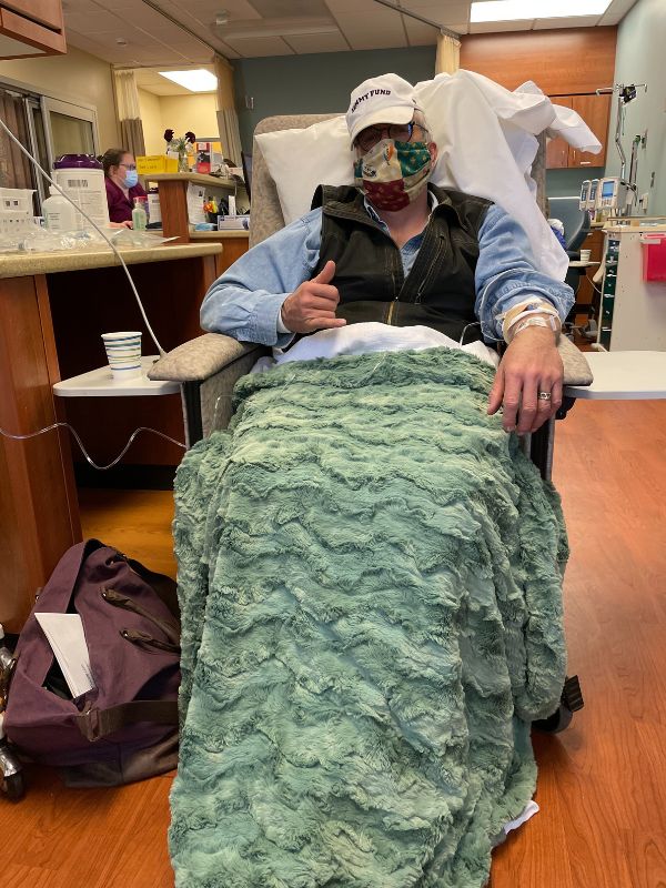 man in hospital chair wrapped in a blanket
