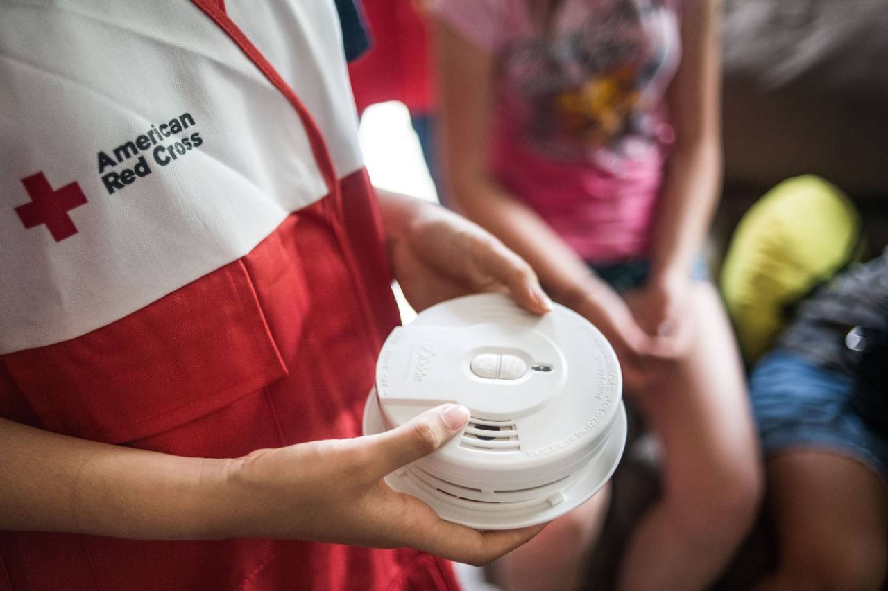 Red Cross volunteer holding smoke alarm