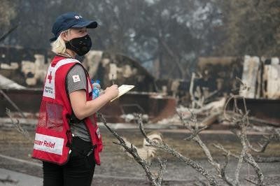 A Red Cross volunteer inspects damage after a wildfire