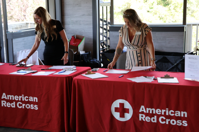 three red cross volunteers in red vest smiling
