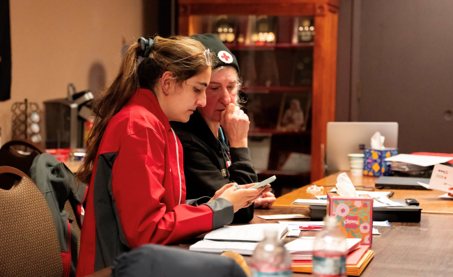 Two Red Cross volunteers sitting at a table.