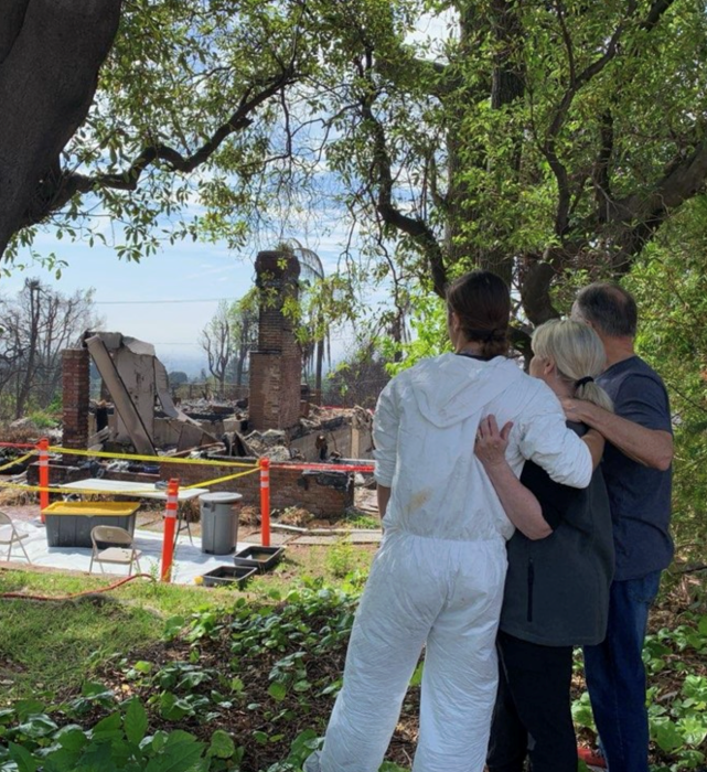 red cross volunteers standing surveying damaged home