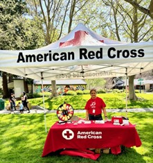 Madhu satnding at a Red Cross table at an event.
