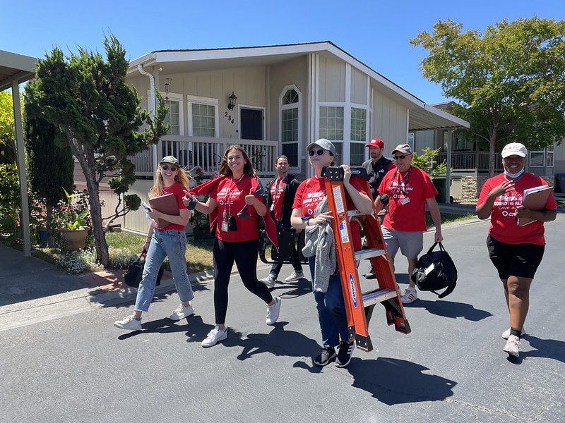 three red cross volunteers walking up to a home