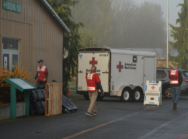 Two Red Cross volunteers walking outside of a shelther.