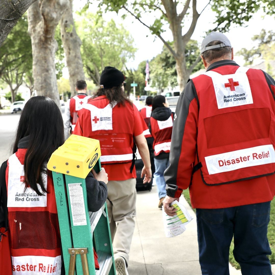 red cross volunteers carry ladders along sidewalk