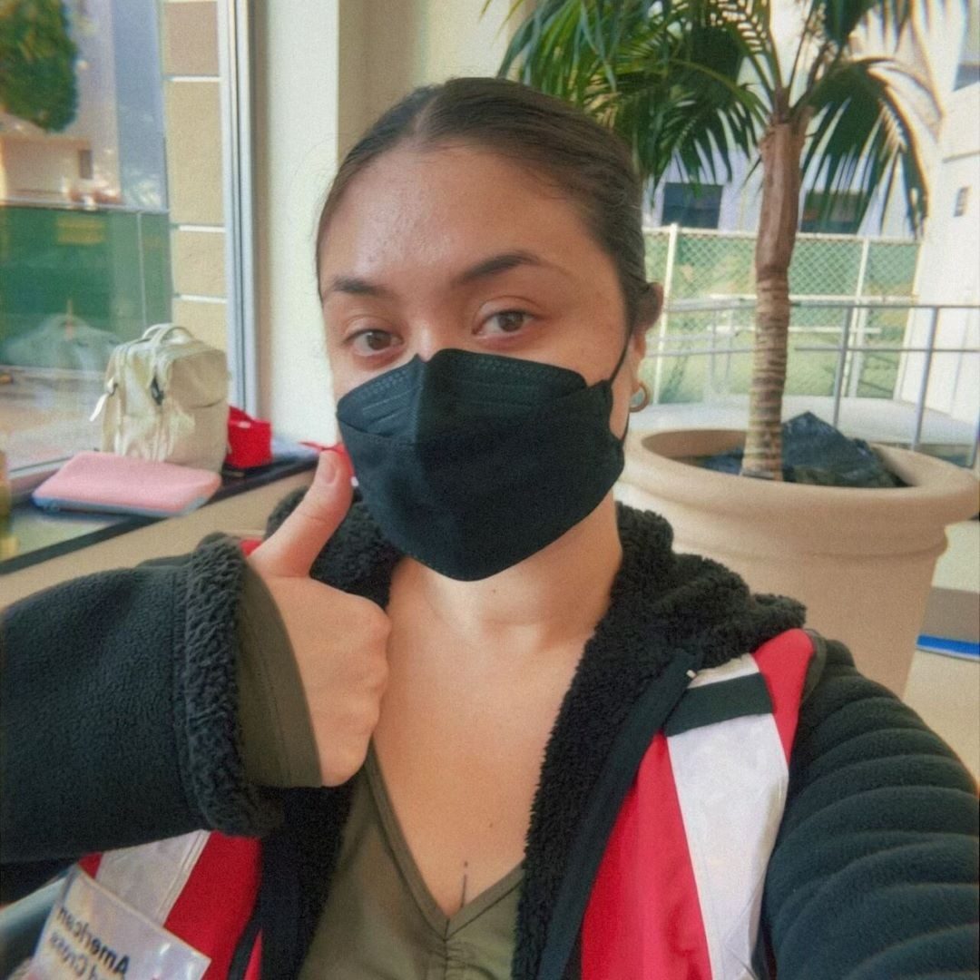 woman with mask on giving thumbs up sign