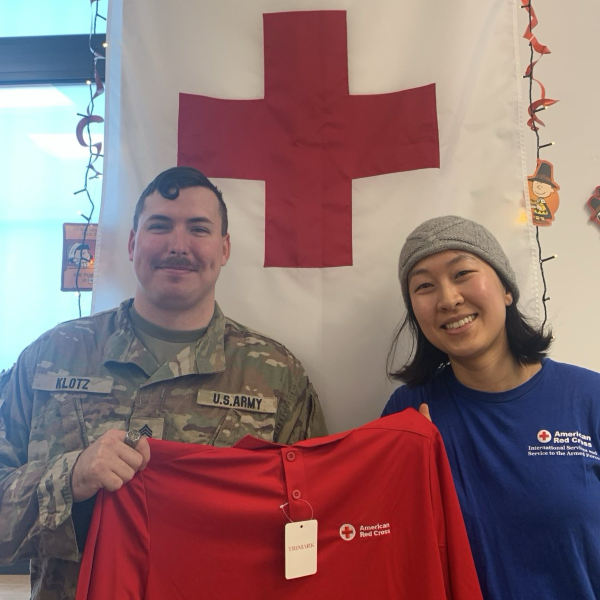 red cross and service member holding up shirt