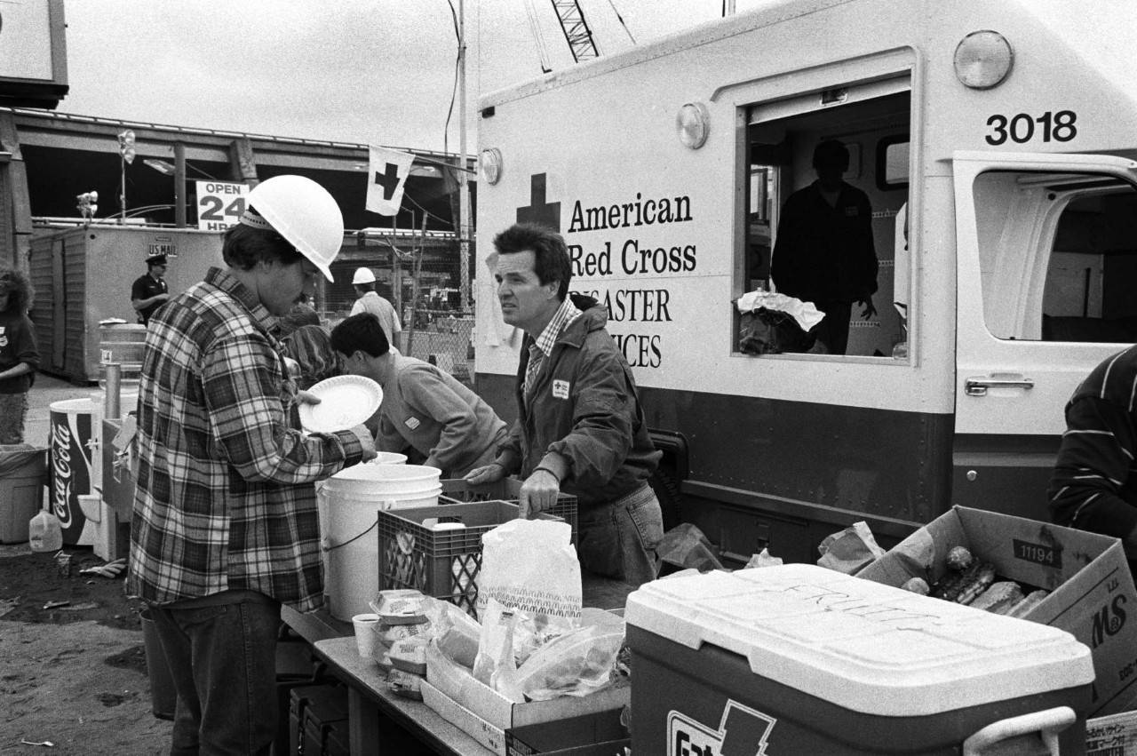 A Red Cross worker provides meals to people near the site of the Cypress Street Viaduct of the Nimitz Freeway Interstate 880 in Oakland, California during the aftermath of the Loma Prieta earthquake.