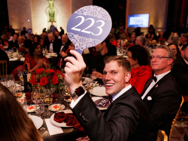 gala attendee holding an auction sign up at group table