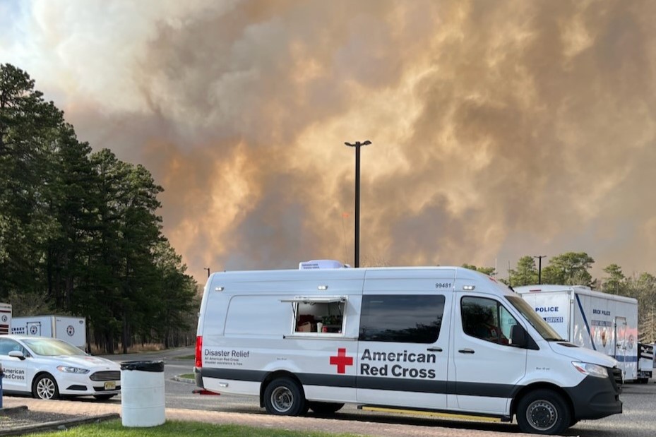 American Red Cross emergency vehicle with wildfire in the background