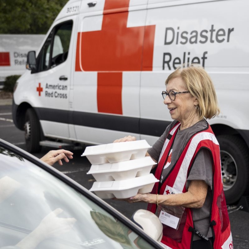 Red Cross volunteer handing out food to clients.
