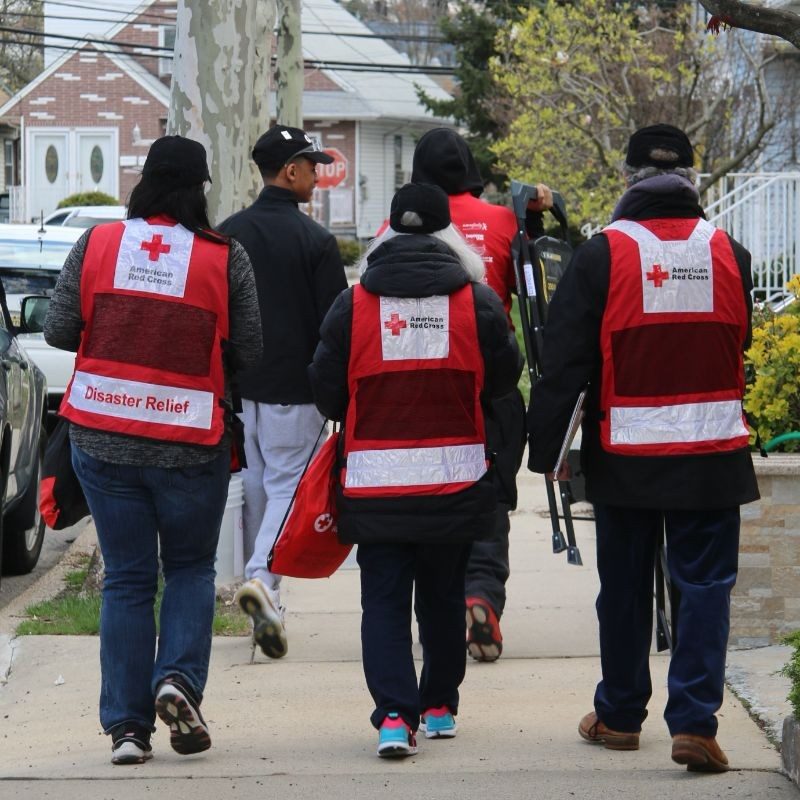 A group of red cross volunteers in vest walking down a street