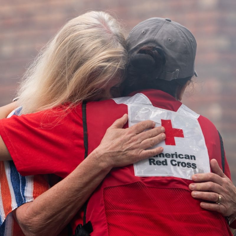 A Red Cross volunteer hugging a crying client