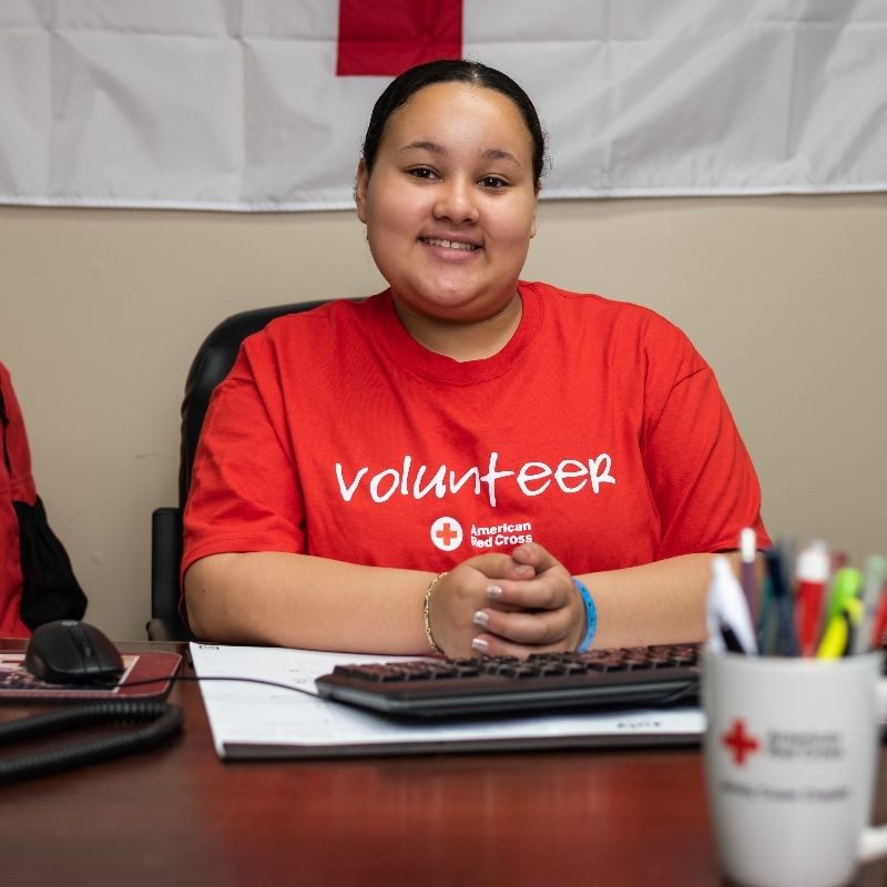 A youth red cross volunteer sitting at a desk.