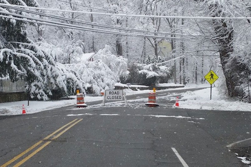 snowy road with closed sign and safety cones.