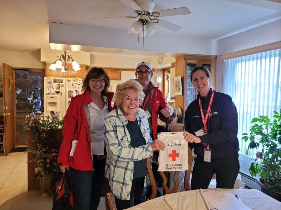 red cross volunteers posing with client in her home 
