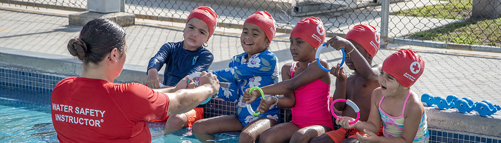 a water safety instructor teaching children how to swim while in the pool.