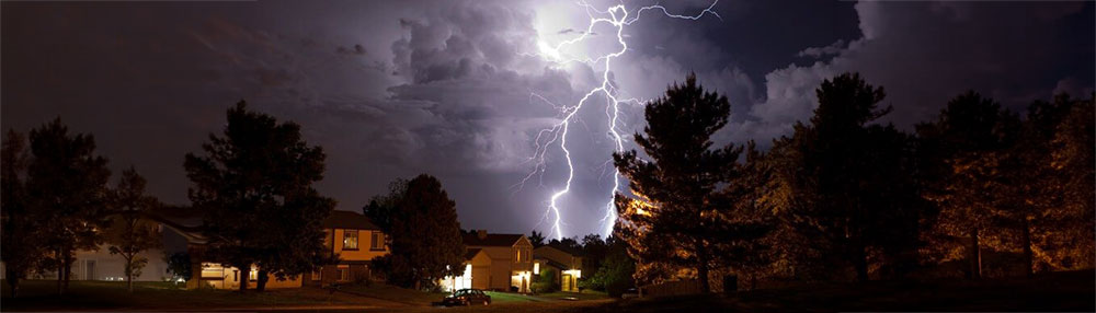 lightning striking above a town in the night sky.