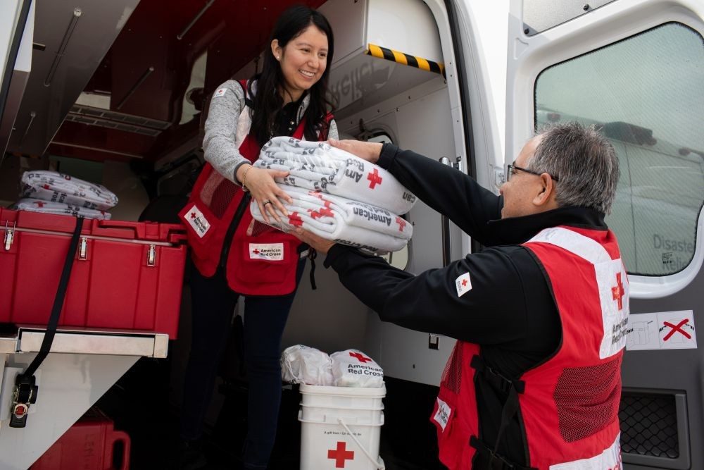 American Red Cross Volunteer handing another volunteer blankets out of a disaster response vehicle.