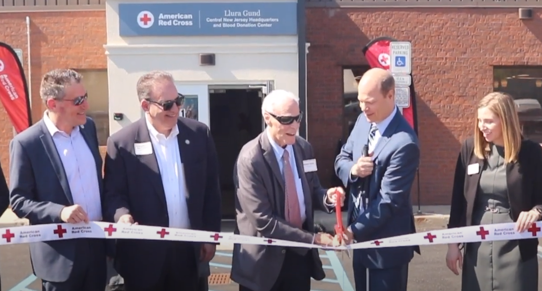 a group of people cutting a ribbon of a new building