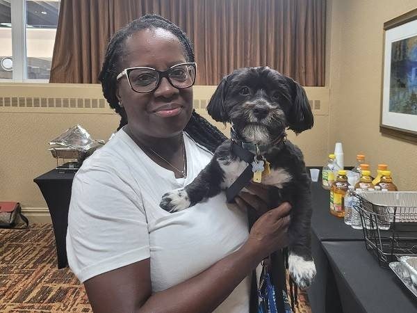 a woman smiling holding her dog