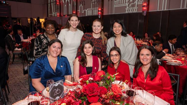 A group of nicely dressed women seated at a table with a floral centerpiece