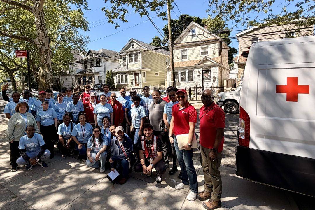 Group of volunteers stand outside near Red Cross vehicle