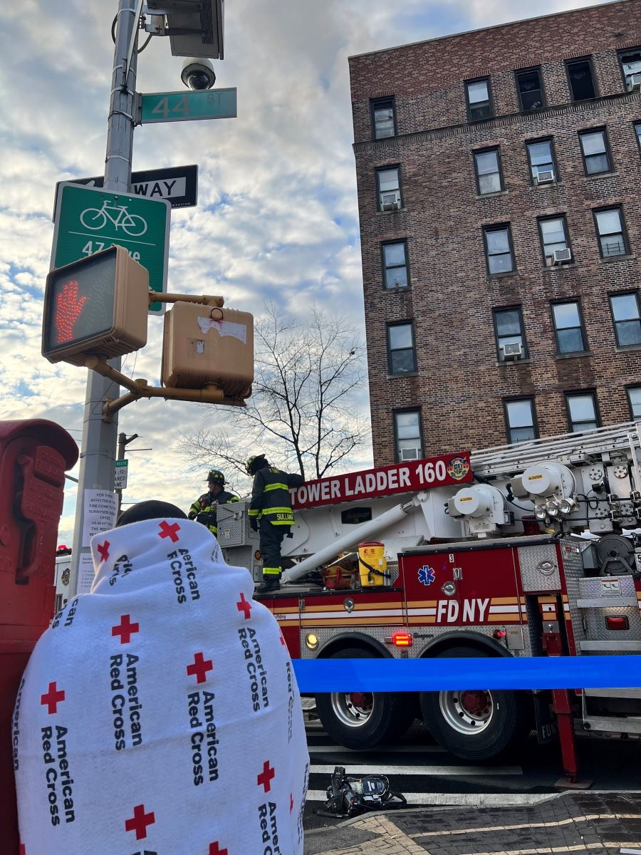 photo of client wrapped in red cross blanket in front of apartment building