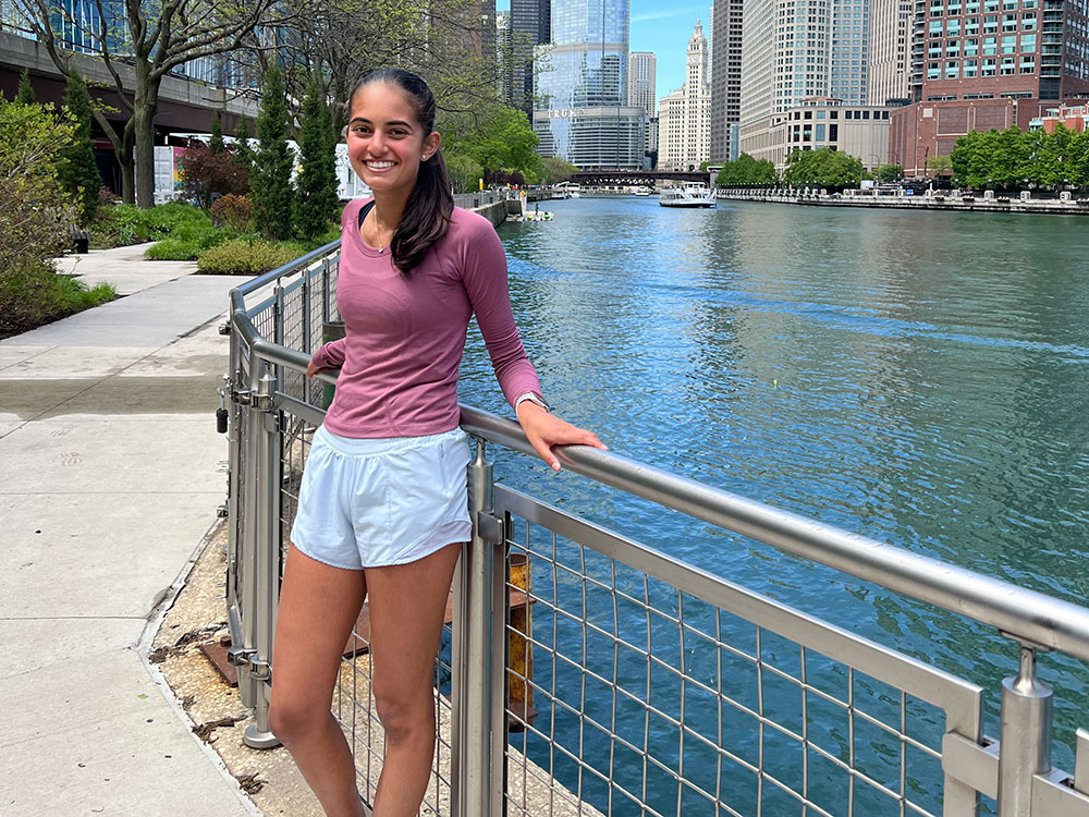 Kajal Parmar, in a running outfit, leaning against a railing next to a body of water.