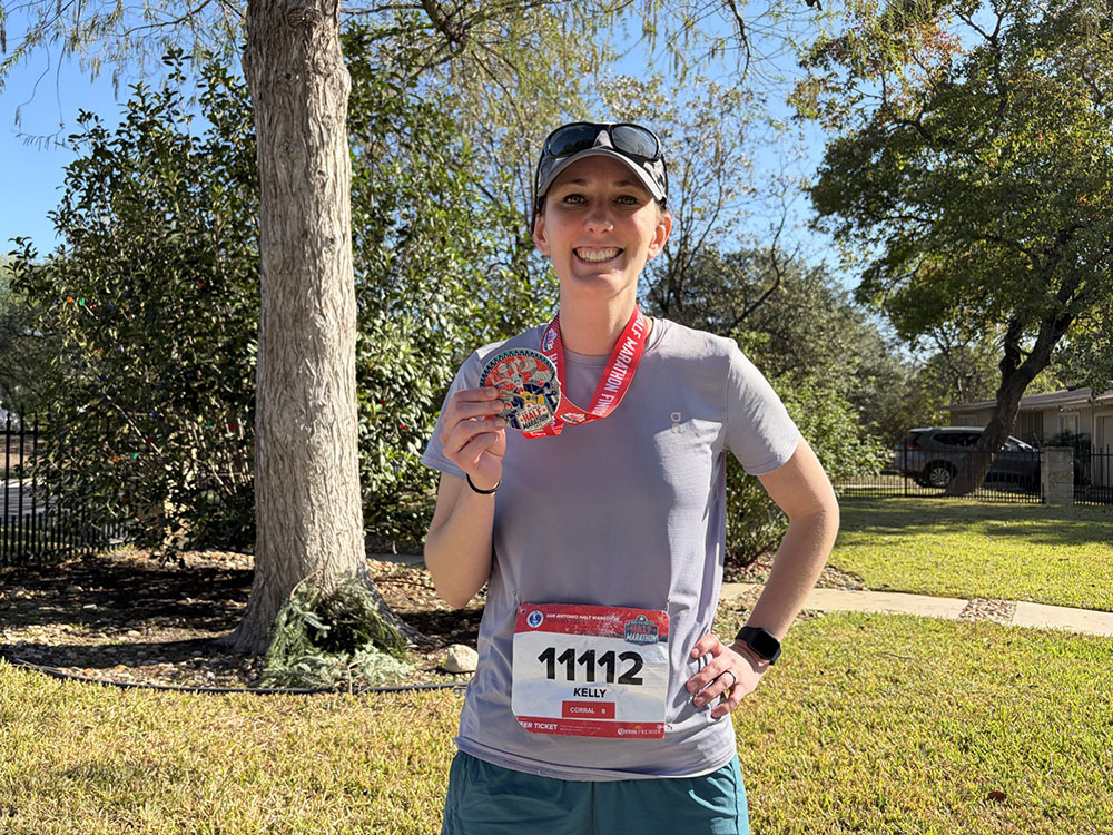 Kelly Spencer, in running outfit, shows the medal she won.