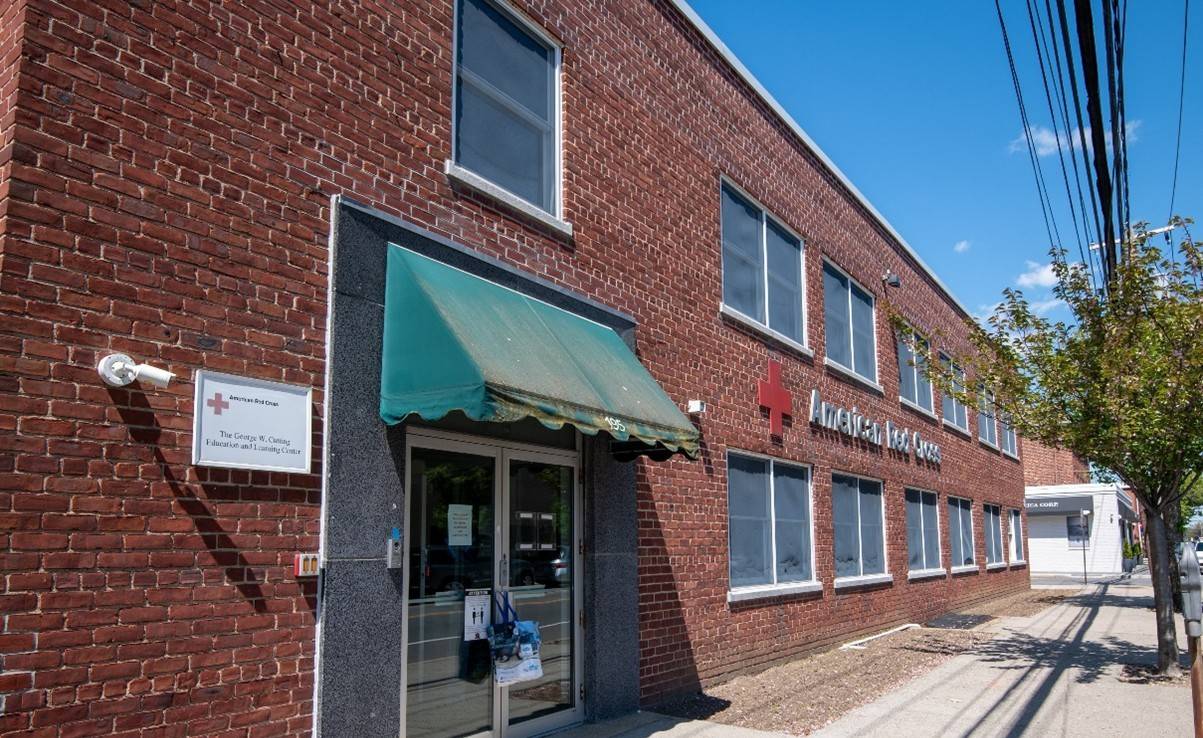 Front of a red brick building with a Red Cross sign