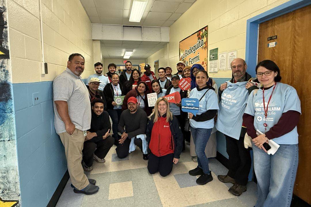 Group of volunteers stand in hallway holding sound the alarm signs