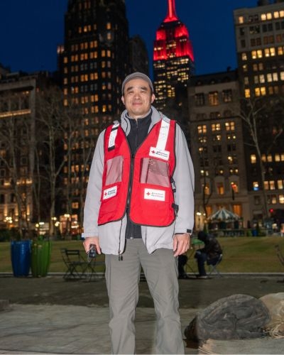 chi in red cross vest with views of buildings