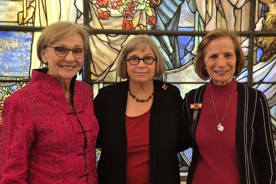 Three women stand in front of Tiffany Circle windows