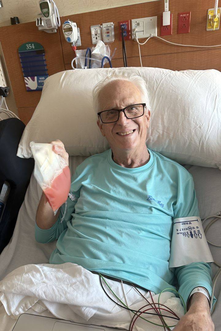 Man holds blood bag while in hospital bed 
