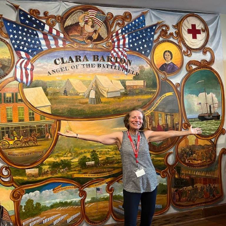 Sue standing in fornt of a Clara Barton mural