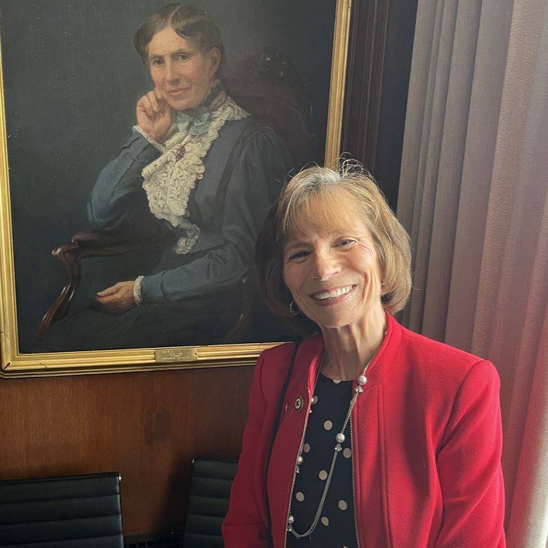 Sue Hassmiller smiling next to a Clara Barton photo