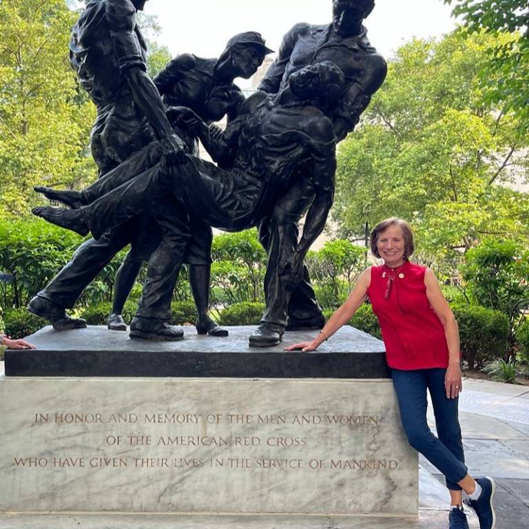 Sue standing next to a Red Cross statue
