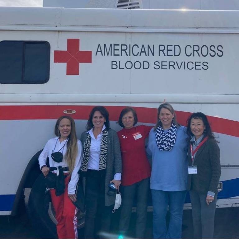 A group of women standing in front of a Red Cross blood donation vehicle