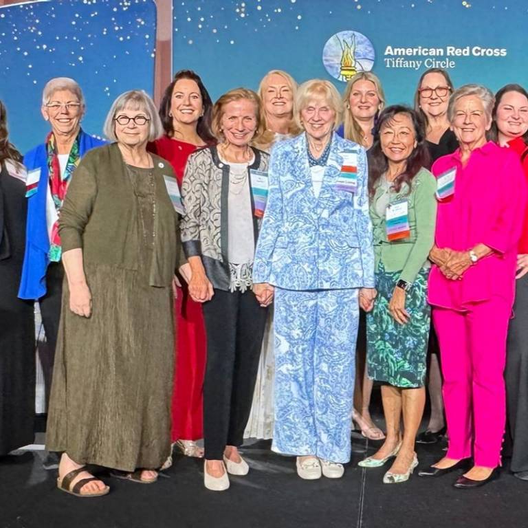A group of women standing in fornt of a tiffany circle poster