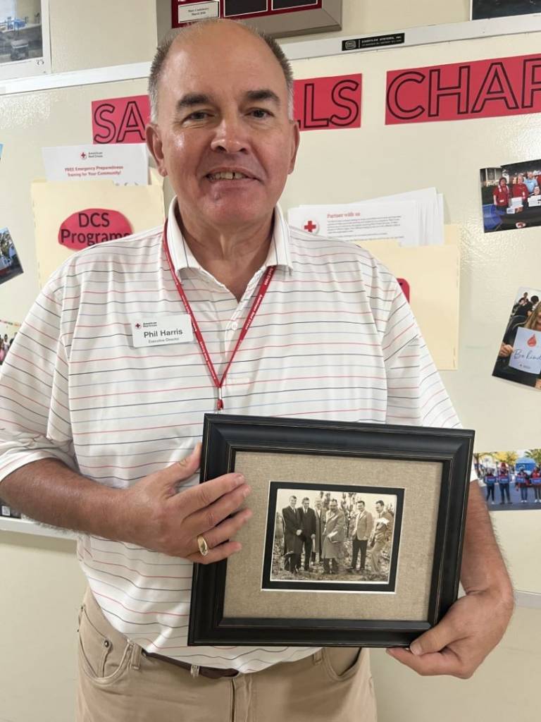 Man stands holding black and white photo in frame
