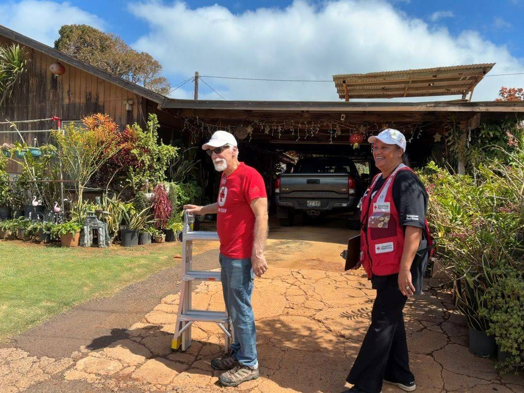 Red Cross volunteers Karl Matzke and U‘i Soares in front of a home at Kaumakani Village. 