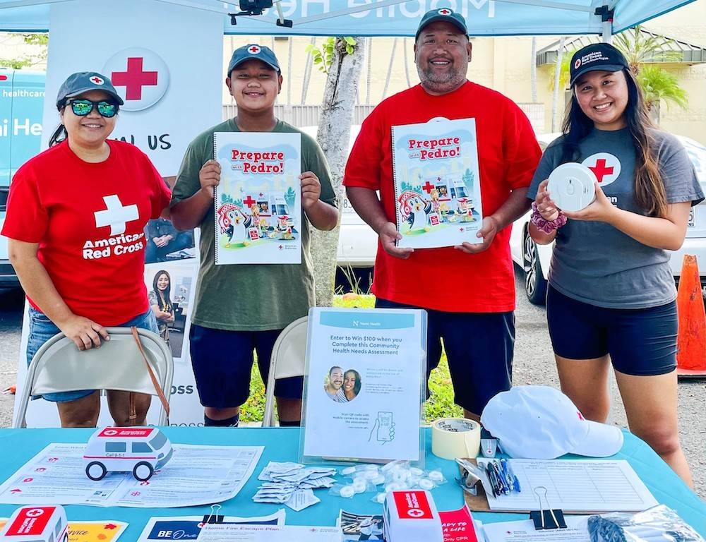 Smiling Red Cross volunteers in Red Cross t-shirts at a preparedness community event.  