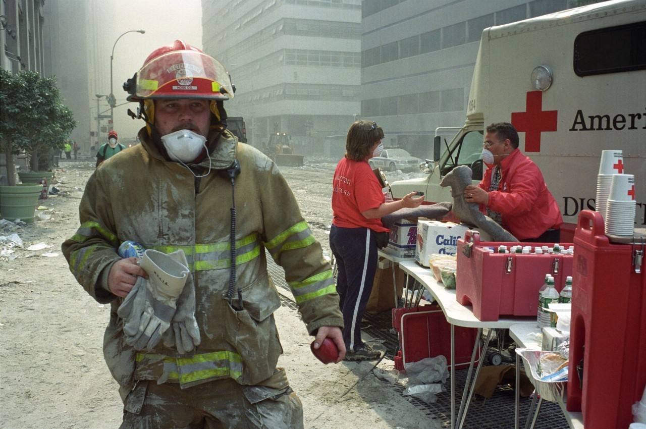A firefighter in the after math of 9/11 next to a Red Cross van passisng out meals. 