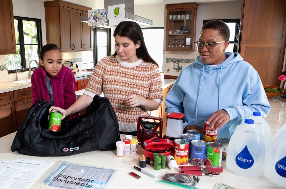 red cross volunteers standing ata table with supplies