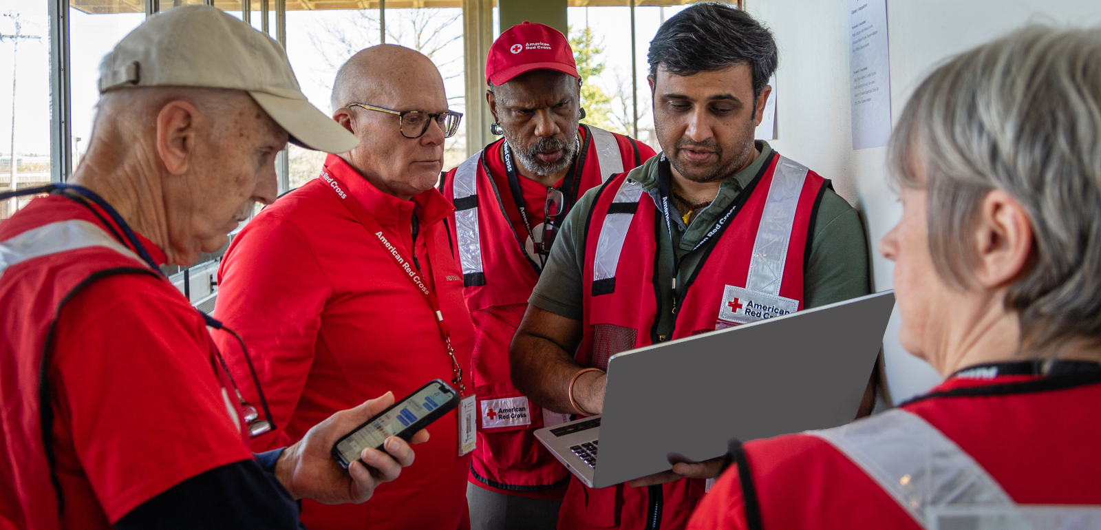 Group of Red Cross volunteers looking at a laptop screen.
