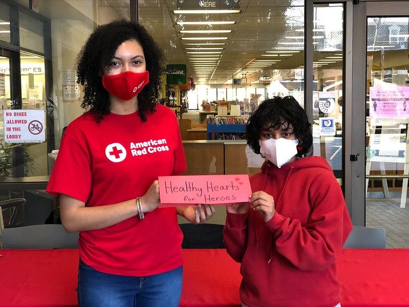 eight teens standing side by side in red cross shirts