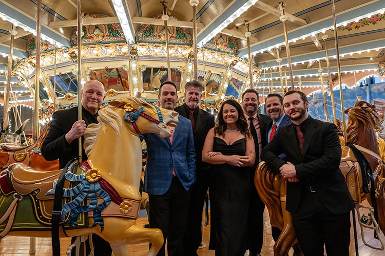 seven people in eveningwear take a grup picture on a merry-go-round.